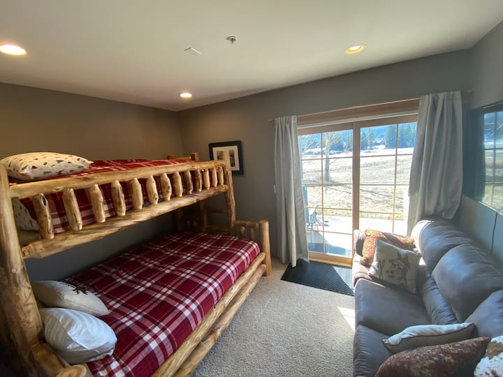 Queen/twin style bunk bed with leather couch and 55” TV above 