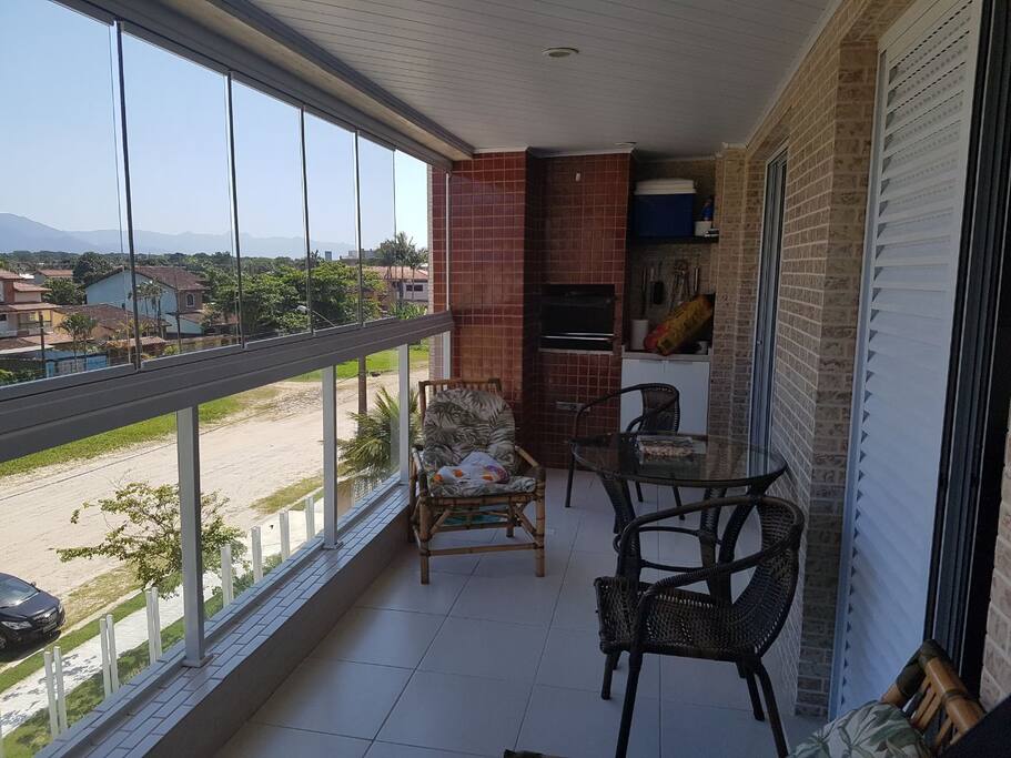 Varanda Gourmet com churrasqueira, mesas e poltronas