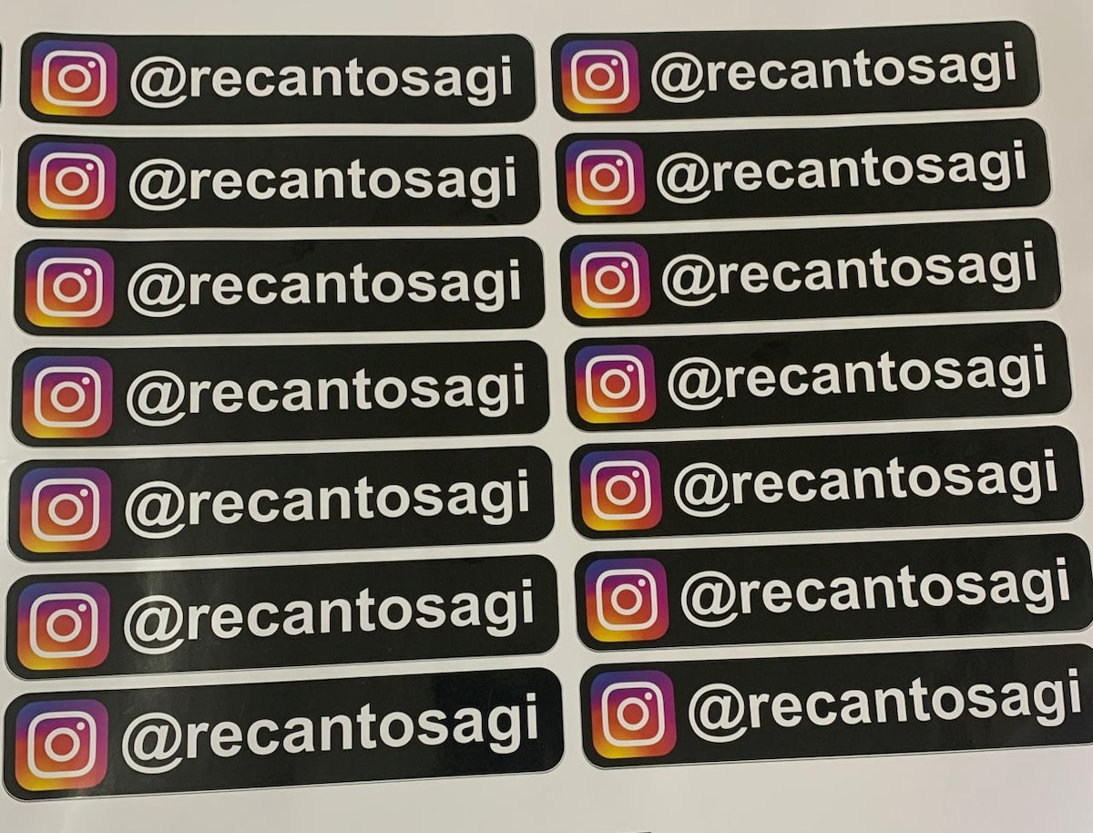 A series of black rectangular stickers is displayed, each featuring the Instagram handle '@recantosagi' in bold white text. The logo's gradient colors are present in a small icon to the right of the handle, providing a modern touch.