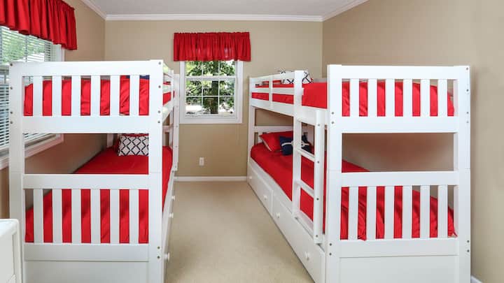 חדר שינה בקומה הראשית עם שני סטים של מיטות קומתיים זוגיות עם מגירות משיכה.