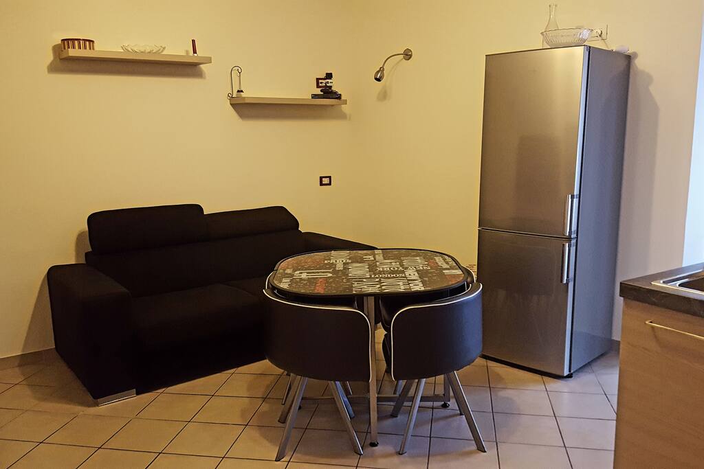 Sala da pranzo 4 persone con divano letto matrimoniale e capiente frigorifero.