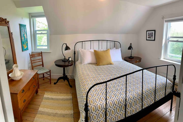 Mucha luz en este dormitorio con una cama queen size. 