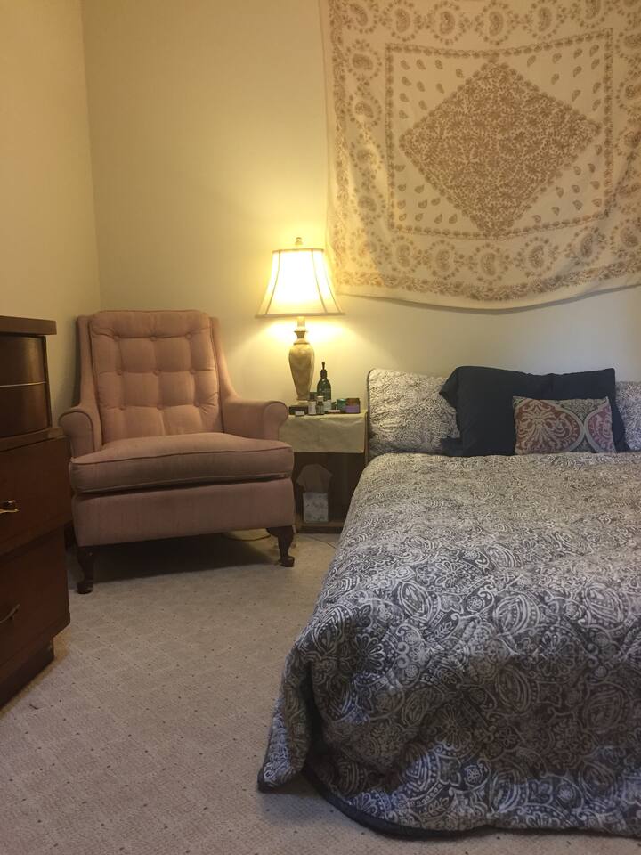 Acogedor dormitorio con cama tamaño queen, sillón y área en el armario para colgar ropa