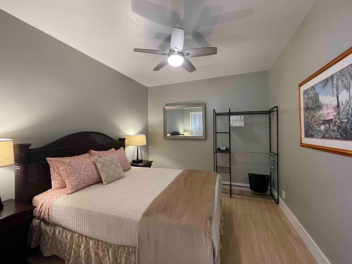 ห้องนอนที่ 2 พร้อมเตียงควีนไซส์ประตูบานเกล็ดและหน้าต่างบานเกล็ดไปยังพื้นที่ห้องนั่งเล่น มีเพียงแสงธรรมชาติที่ส่องผ่านหน้าต่างบานเกล็ดและประตูบานเกล็ดเท่านั้นไม่มีหน้าต่างจากภายนอกบ้าน 