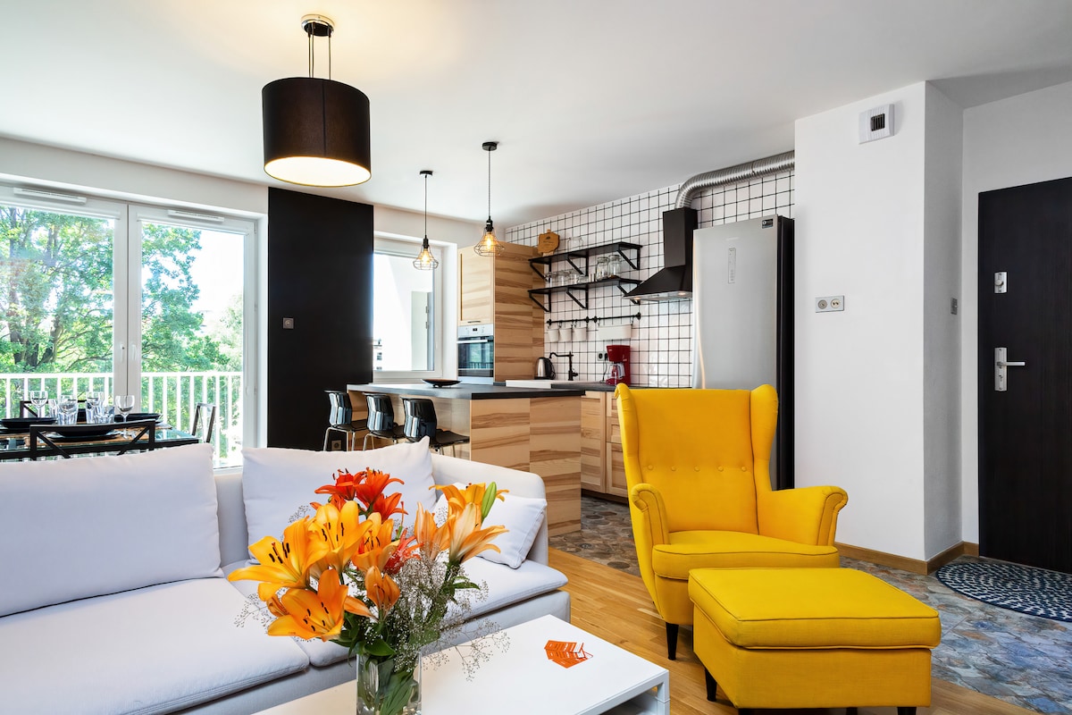时尚的客厅，配有充满活力的黄色扶手椅、现代沙发和装饰着鲜花的咖啡桌，周围有大窗户，自然光线充足。
