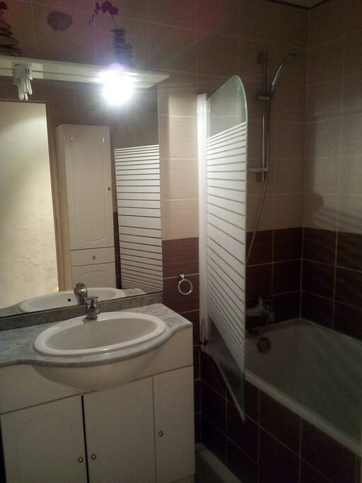 Salle de bain équipée d'une baignoire, d'un lavabo et des rangements nécéssaires.