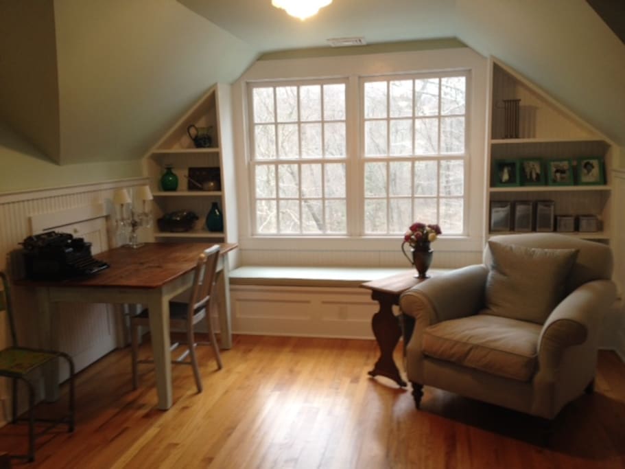 Sitting area of bedroom, with desk and comfortable reading chair, overlooking pond on property.