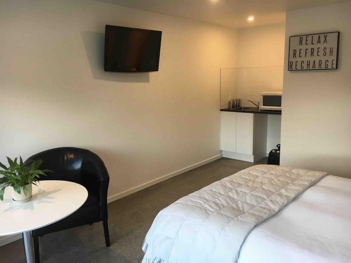 Malá kuchynka s čajom a zariadením na prípravu kávy. Vysoká chladnička na lavičke, mikrovlnná rúra.