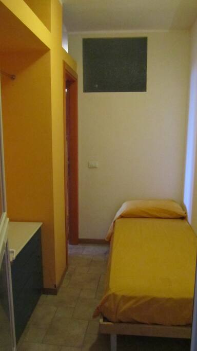 Stanza con letto singolo, cassettiera e armadietto