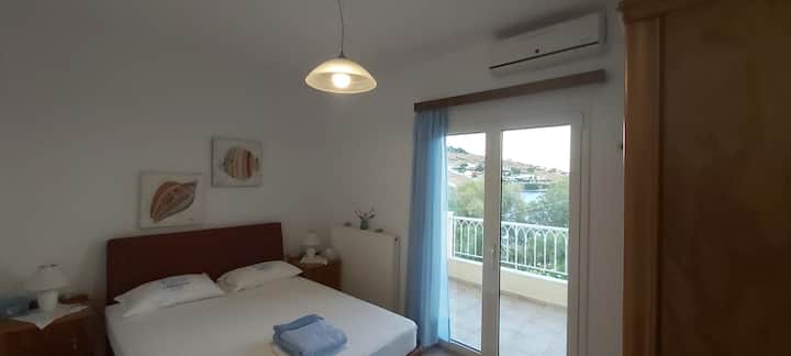 Dormitorio principal.  Increíble vista  al mar Egeo. Simple y práctico. Con una cama tamaño queen, unidades de almacenamiento con dors, TV  y su propio balcón.