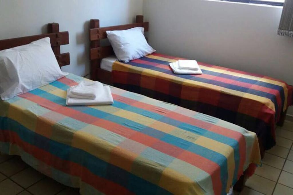 Segundo quarto com split, duas camas de solteiro, camiseiro e 1 sofá cama.