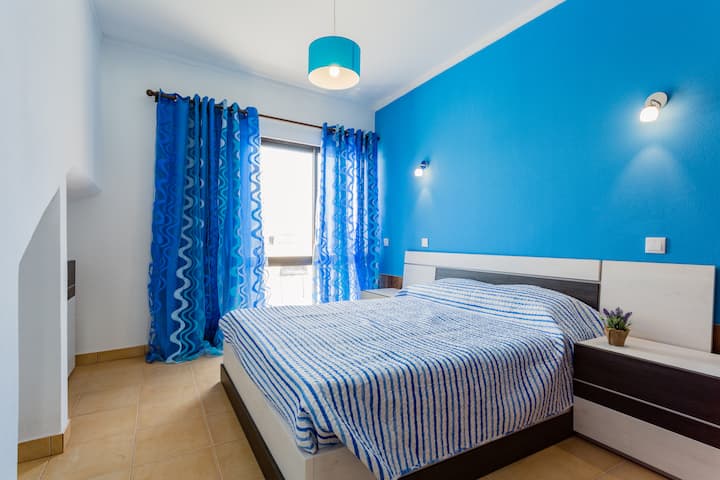 חדר השינה מעוצב גם בכחול. יש לו גישה למרפסת הפרטית.