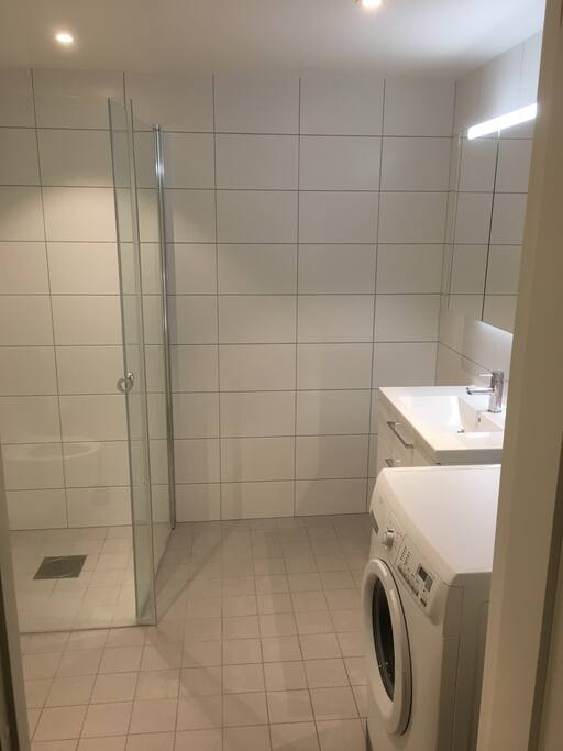 Bad med toalett, dusj, vask og vaskemaskin.
Bathroom with toilet, shower tray, washbasin and washing machine.
Baño con váter, plato de ducha, lavabo y lavadora.