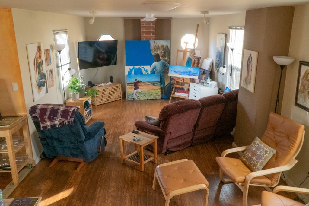 Shared living room with big screen TV, Apple TV (Netflix, Apple Music, etc.), work desk, reading nook, and original art.