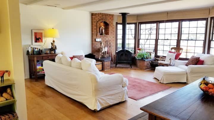 ห้องนั่งเล่นในเมนคอทเทจมีตัวเลือกที่นั่งที่สะดวกสบายมากมายและเตาเผาฟืนแบบชนบท