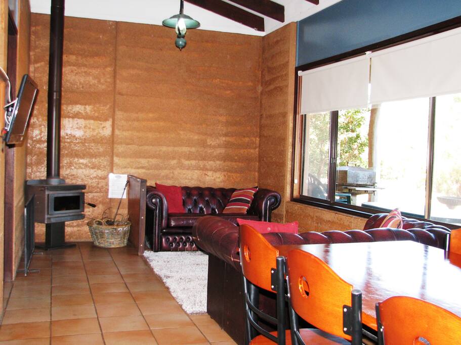 Comfortable open plan living room with chesterfield couches, lake views and and wood fire (firewood supplied).