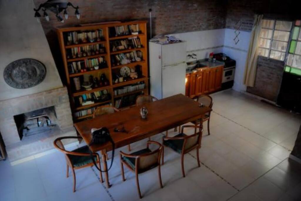 Espacio común tipo cocina comedor living con televisión, chimenea y sofá