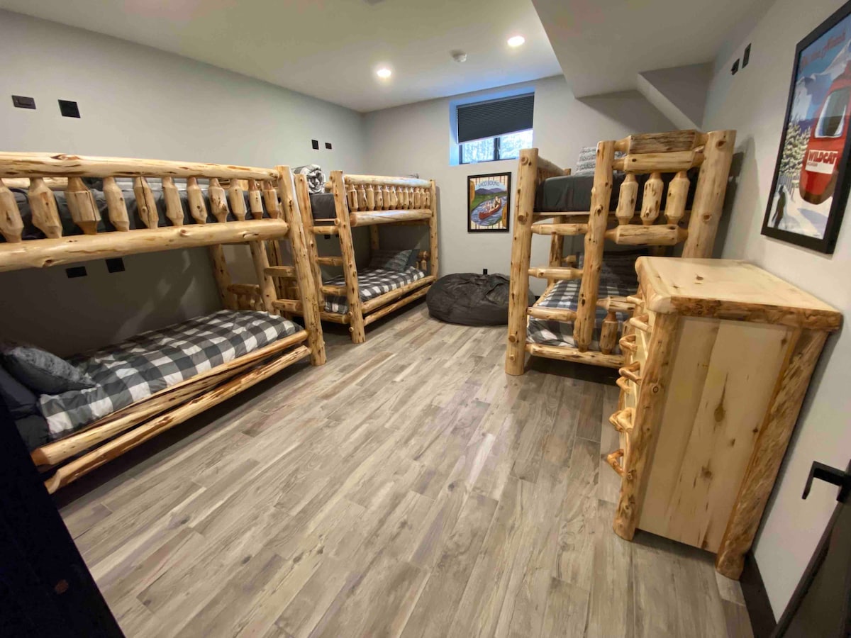 غرفة بطابقين في الطابق السفلي تحتوي على 6 أسرّة بطابقين مصممة خصيصًا تتميز بأضواء قراءة فردية ومنافذ شحن.  