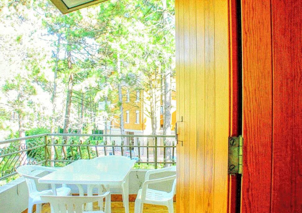 Offre piena vista sulla pineta dalla terrazza attrezzata con tavolo e sedie.