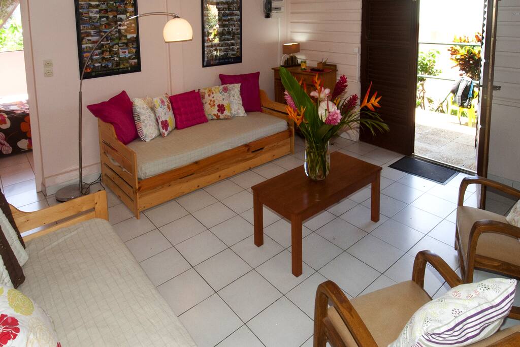 le salon de plein pied sur la terrasse, vue mer des caraïbes et village. plage et commerces à 300 mètres. 2 canapés lits avec moustiquaire, aération par lames ventilantes et ventilateur. WIFI, TV TNT.