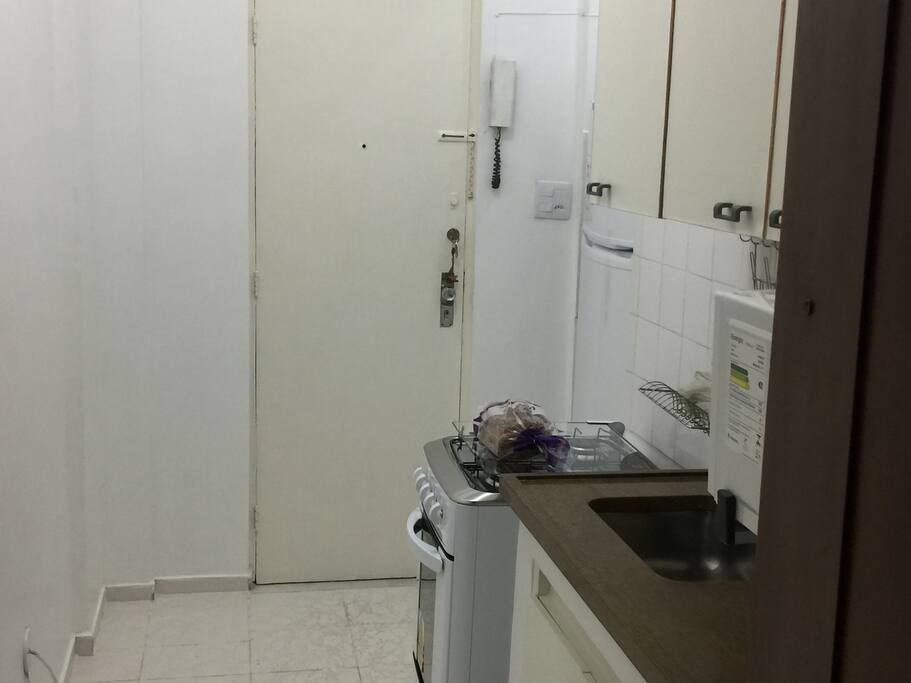 Cozinha (geladeira, fogão, forno microondas, cafeteira, sanduicheira-grill, liquidificador, pratos, copos talheres, armários e pia grande).