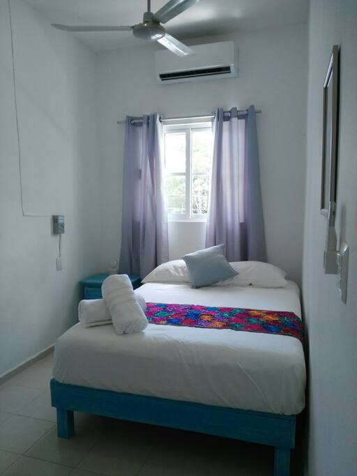 Bedroom a Doble bed, bath towels a small lamp on the bureau, a mirror on the wall, A.C remote and roof fan.