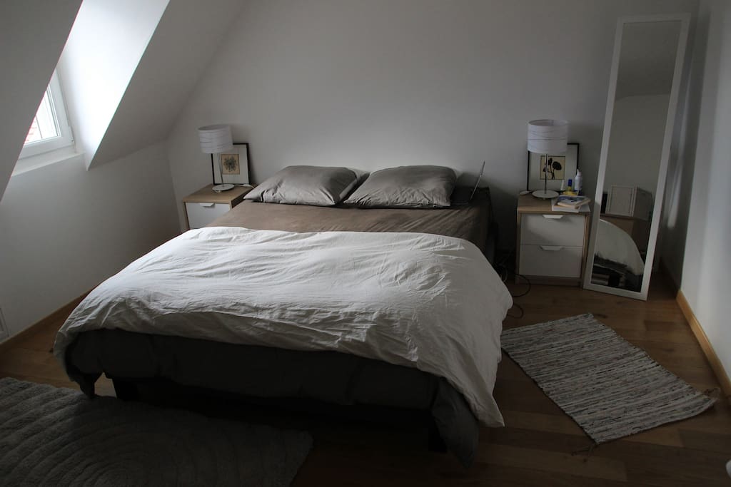 Lit queen size avec deux tables de chevets, espace de rangement pour les habits et porte chemises