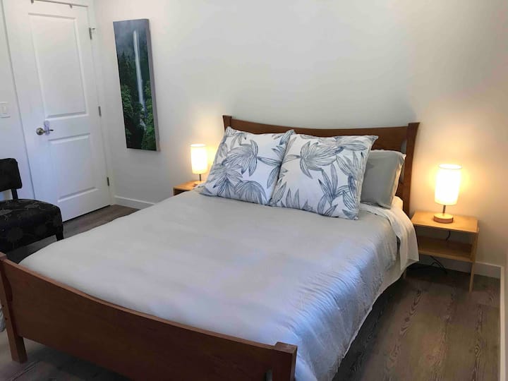 Una cama queen de látex hipoalergénico natural en un marco de madera maciza, sábanas de bambú suaves, un edredón de bambú, lámparas de contacto con cargadores USB y cuatro almohadas queen te esperan con dos almohadas extragrandes de Tommy Bahama para relajarte.