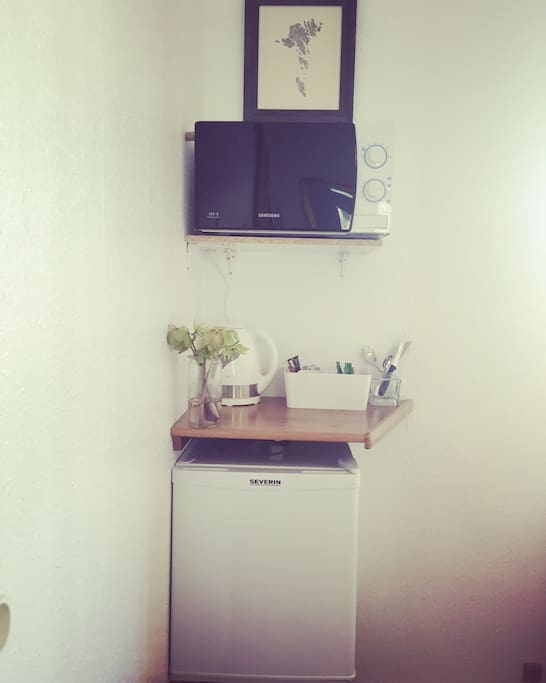There is a fridge available. A water cooker, tea, coffee, a cup and a glass, and cutlery.
