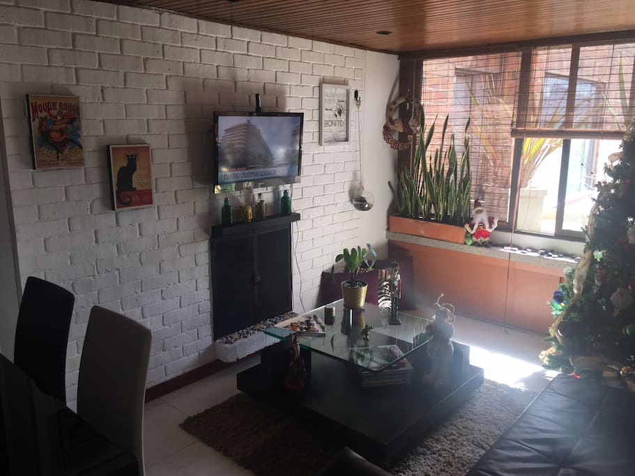 Salón acogedor lleno de luz en un ambiente tipo vintage por sus paredes en ladrillo blanco y el techo en madera inspirado en los años 80's