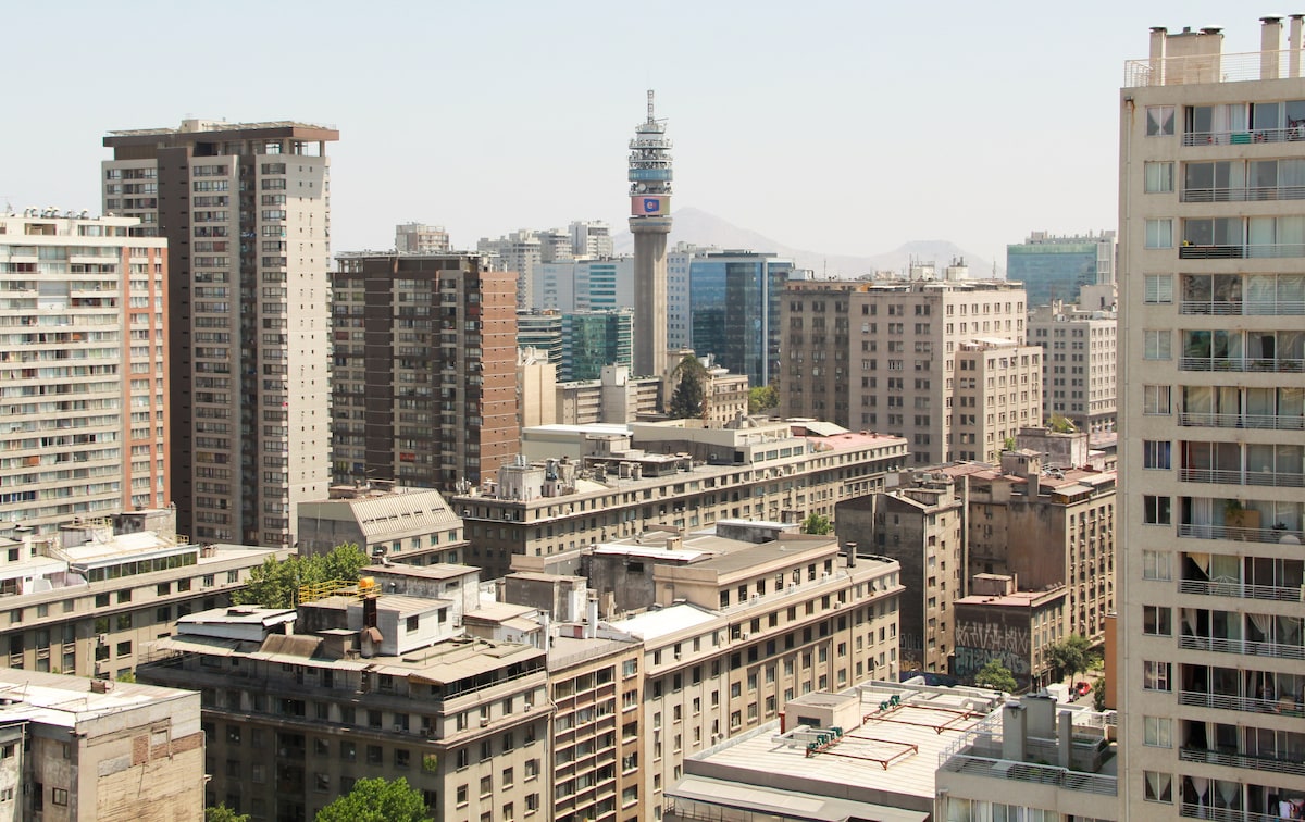 A panoramic view showcases a bustling urban landscape filled with various high-rise buildings and historical structures. A prominent tower stands central in the background, while the surrounding architecture reflects a blend of modern and classic designs, offering a glimpse of the city’s vibrant atmosphere.
