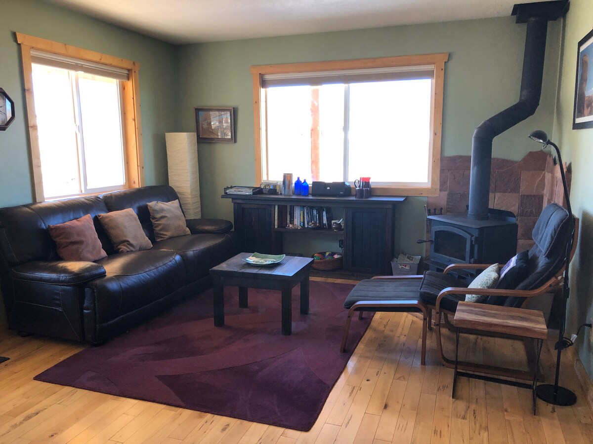 Sala de estar. Suelo de arce, estufa de leña con salpicadero de roca roja creado localmente. Toques rocosos rojos desde Bernie Skydrummer.