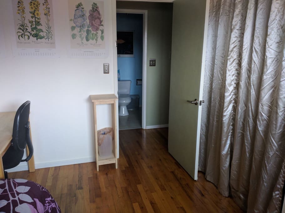 Bedroom across hall from shared bathroom + closet with hangers.