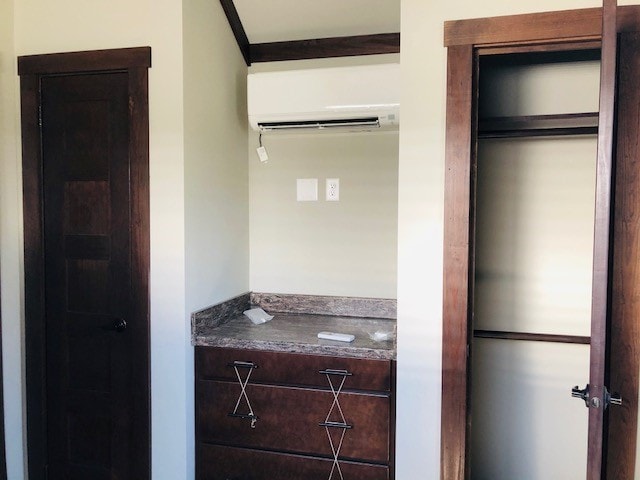 A built-in dresser with multiple drawers is positioned along a wall in the room. Above it, an air conditioning unit is mounted. A closet with an open door is visible to the right, providing additional storage space. The walls are painted light, complementing the wooden doors.
