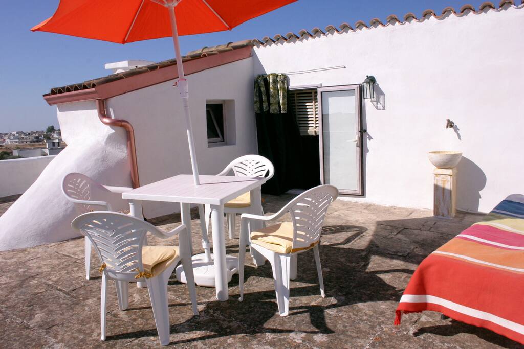 Terrasse plein soleil avec lit de repos, fontaine et douche