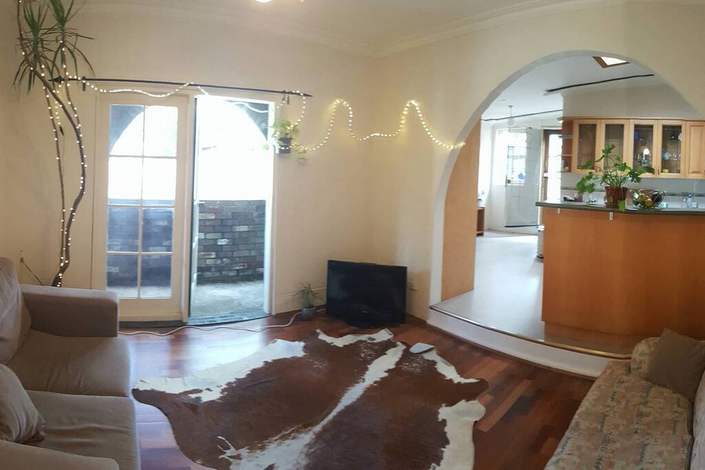 Cosy lounge room with plenty of seating which opens up to an outdoors area and also spacious open planned kitchen