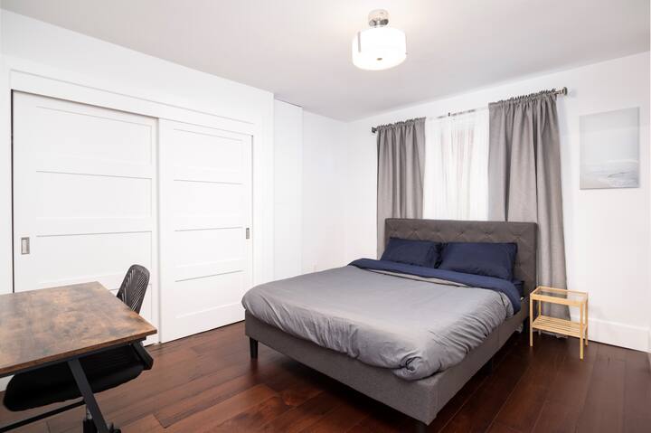 חדר שינה מרווח עם מיטת קווין סייז, שולחן עבודה וארון גדול. 