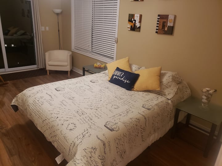 غرفة نوم في الطابق الرئيسي 1 مع باب فناء للمشي إلى السطح والشاطئ.