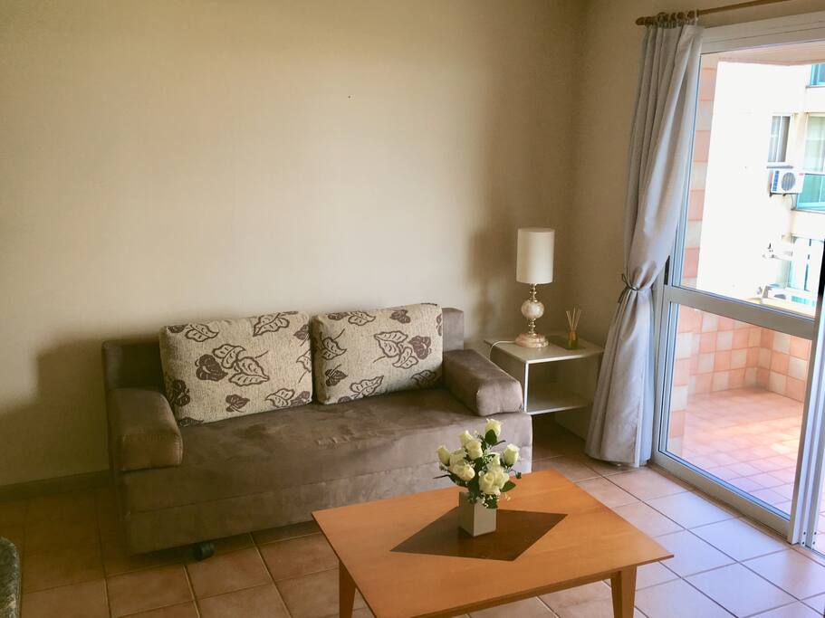 Detalhe da sala com o recente sofá-cama de casal junto à sacada com vista para o mar e nova Smart TV 40 polegadas.