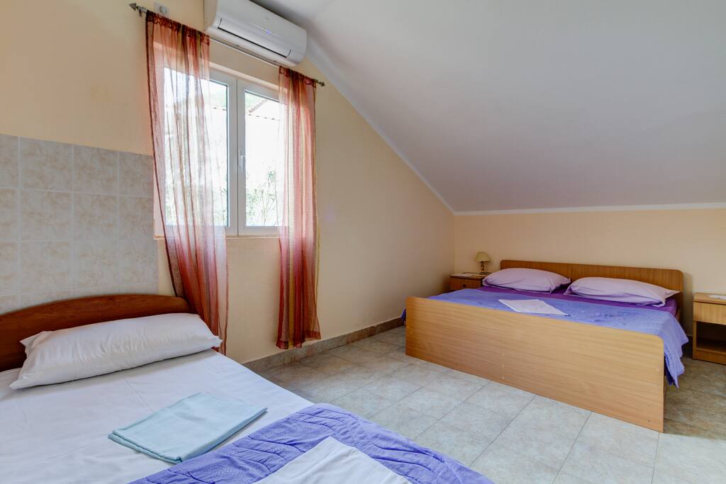The bedroom has a large double bed and another bed and the window in the room also gives a view of the sea and the mountains.