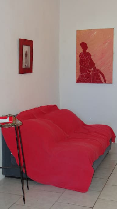 Petit salon intérieur avec canapé lit, et fenêtre ouverte sur le jardin