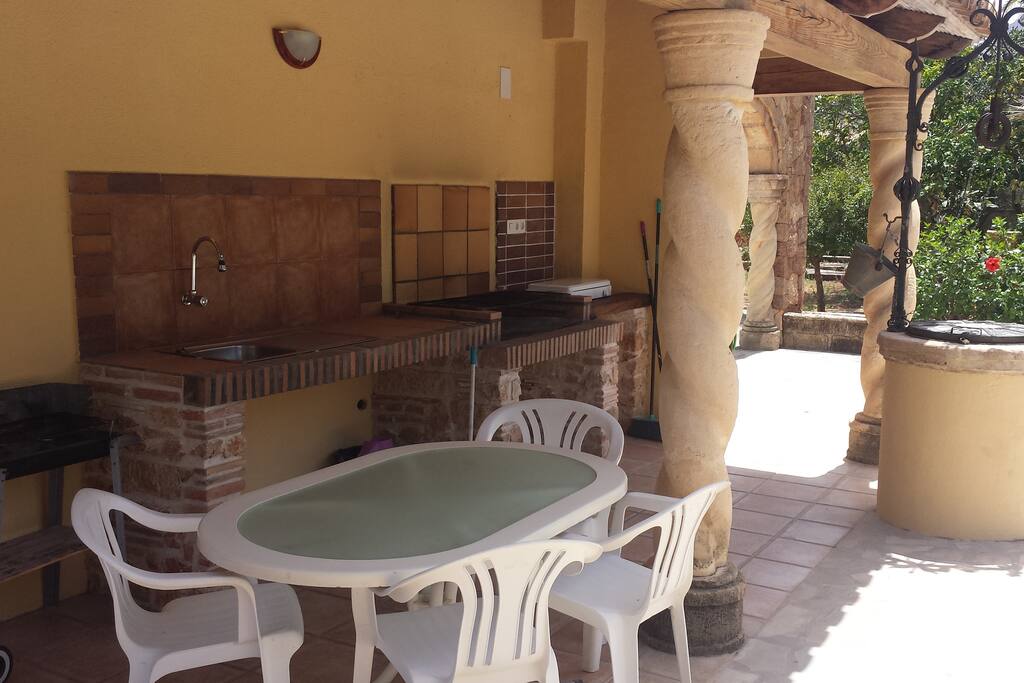 Terraza cubierta junto a piscina con barbacoa