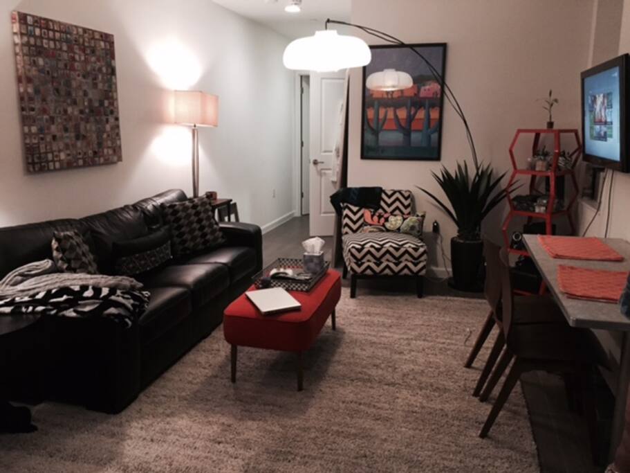 Large living room with TV, comfy couch, funky decorations and a full-sized dining room table.