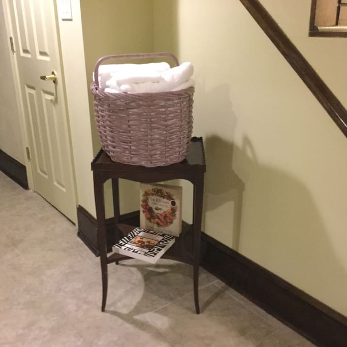 Cherry wood stand holding a basket of fresh towels and washcloths
