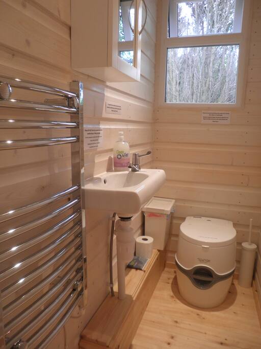 toilet area with heated towel rail, hand basin and portable loo.
