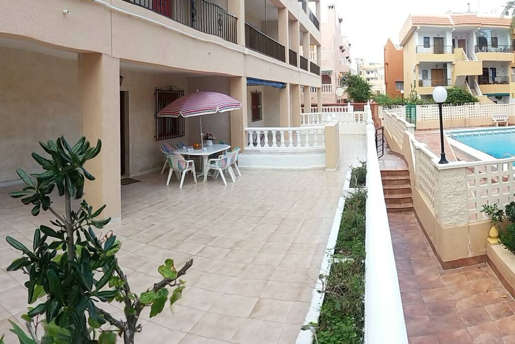 Amplia terraza con mesa y sombrilla para tomar el sol, tumbarse a la sombra y disfrutar de una conversación con vistas a la piscina.
Large terrace with table and umbrella to sunbathe, to lie in the shade and to enjoy a conversation with views of the pool.