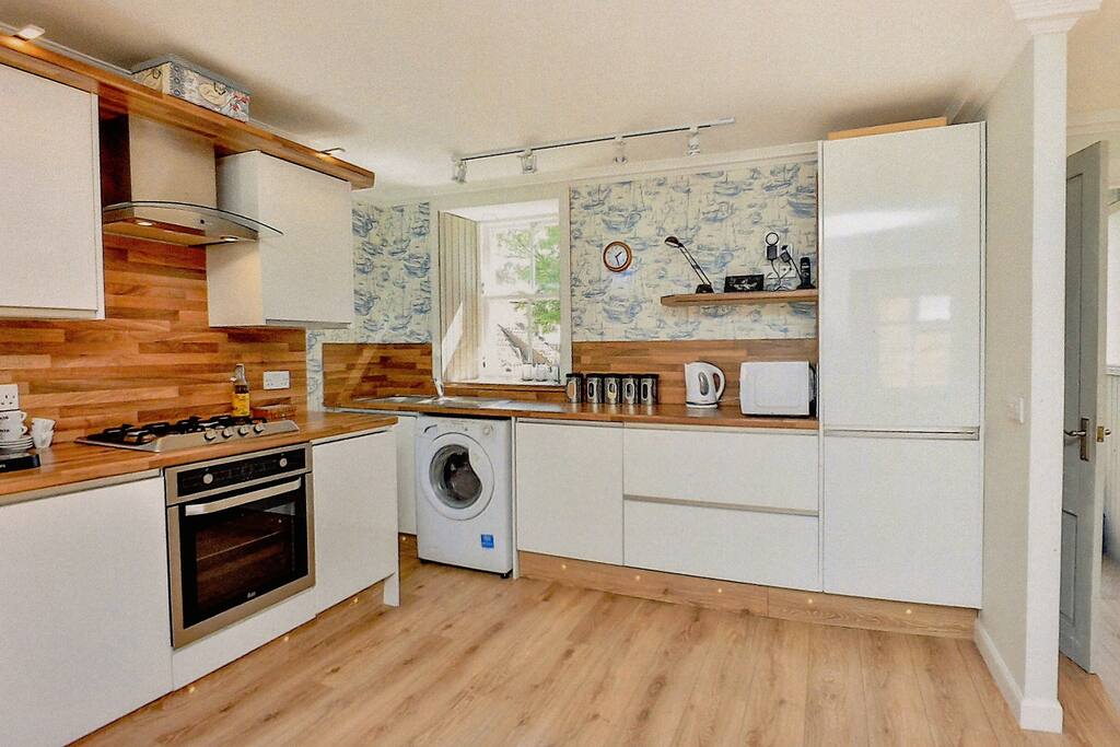 Kitchen end of open plan room. Includes dishwasher and washing machine.