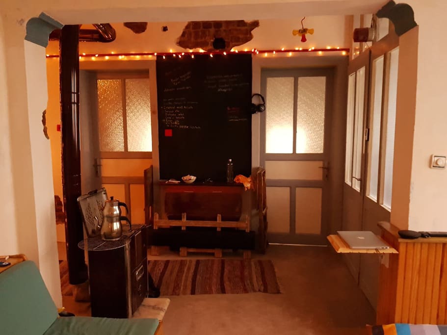 Perspective taken from the leaving room. Door to the left leads to the room you will be staying in. The black wall is a chalkboard. We have inspector gasket style tables and chairs underneath that open when in use. We also have an old fashioned fire heater.