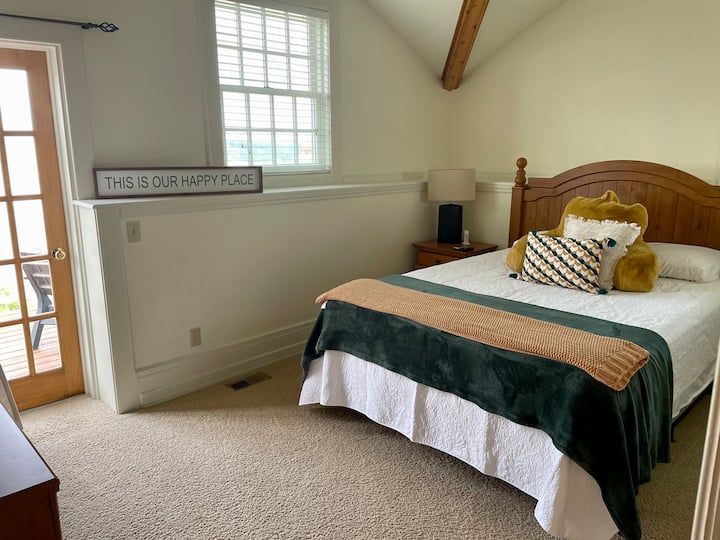 غرفة نوم للضيوف في الطابق العلوي بسرير بحجم كبير وشرفة خروج