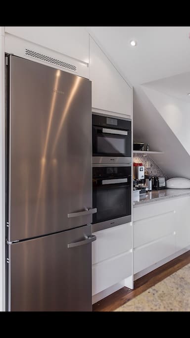 A fully equipped kitchen with an extra large refrigerator, oven, microwave and toaster.